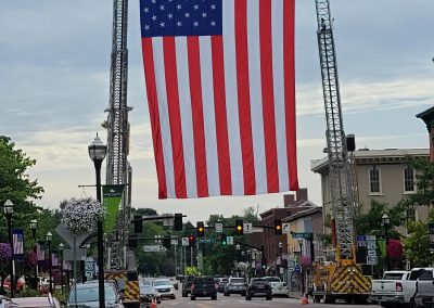 Large flag suspended by fire trucks