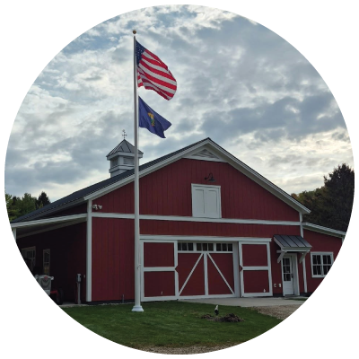 US and Vermont Flags flying on a pole in front of a red building